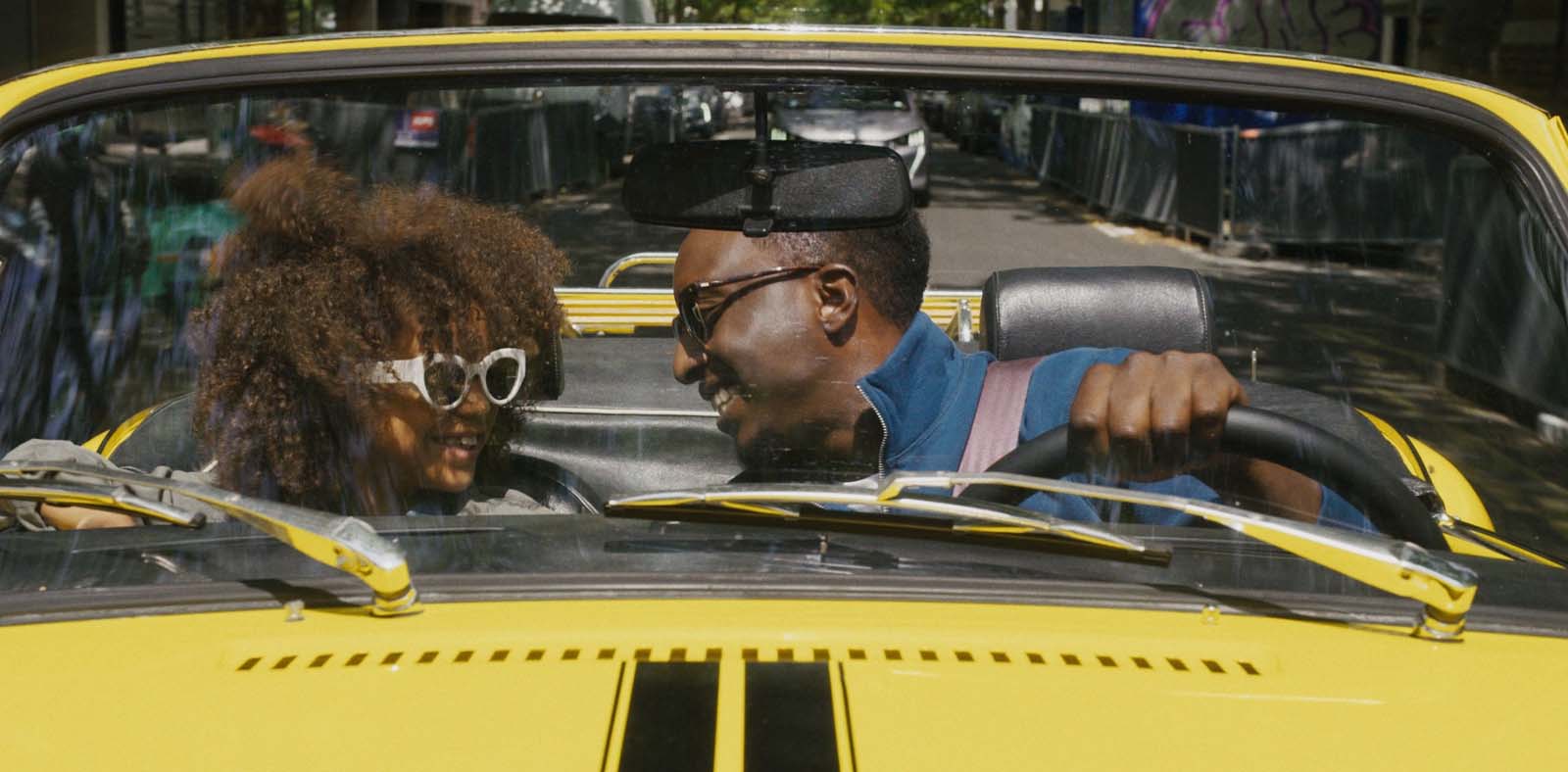 Photo issue du film Super papa où deux personnes sont dans une voiture décapotable jaune.
